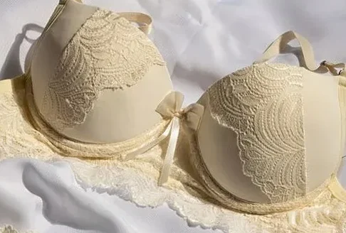 Cream lace bra with scalloped lace panels laid flat on white fabric