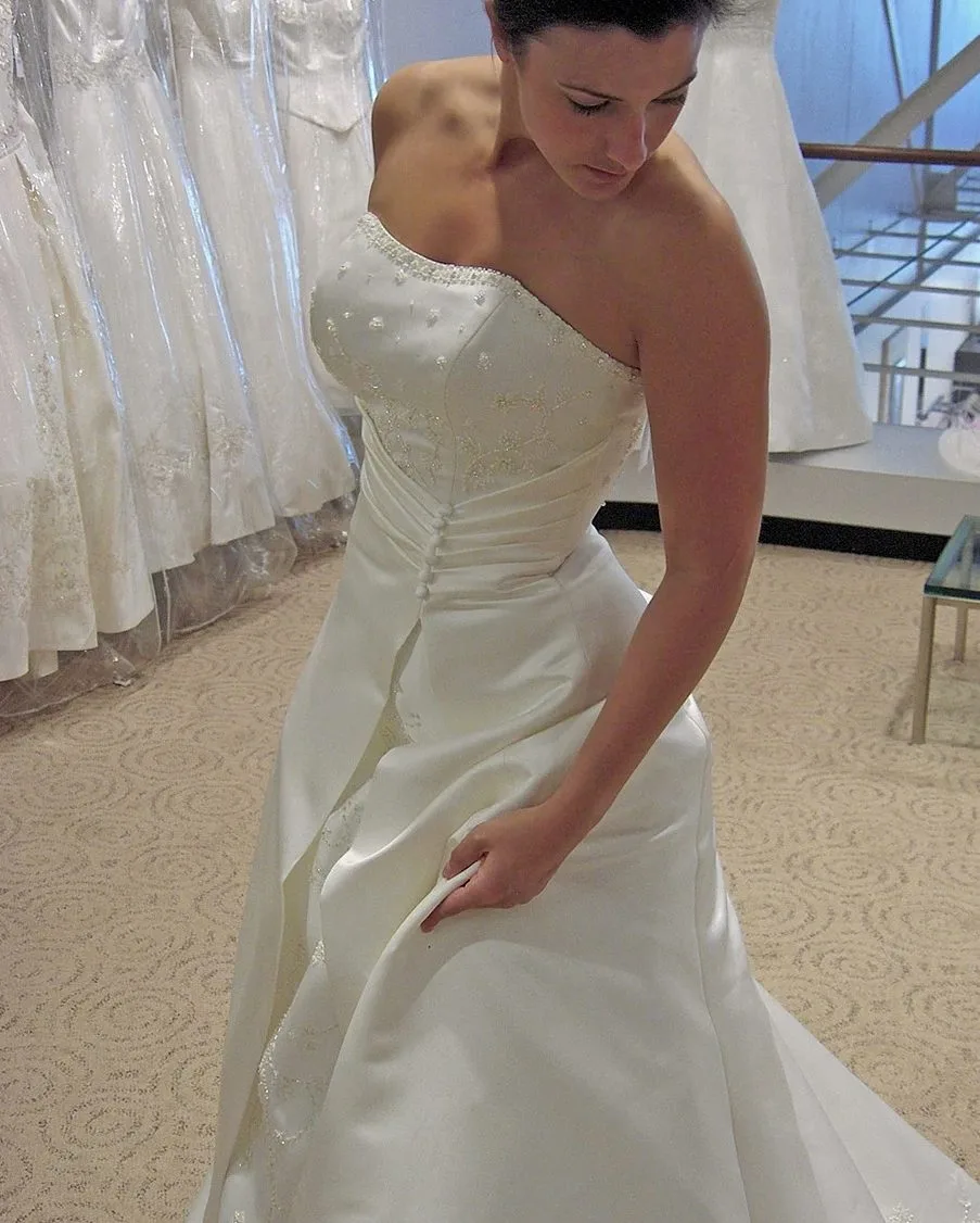Woman in a strapless satin wedding gown at a bridal salon