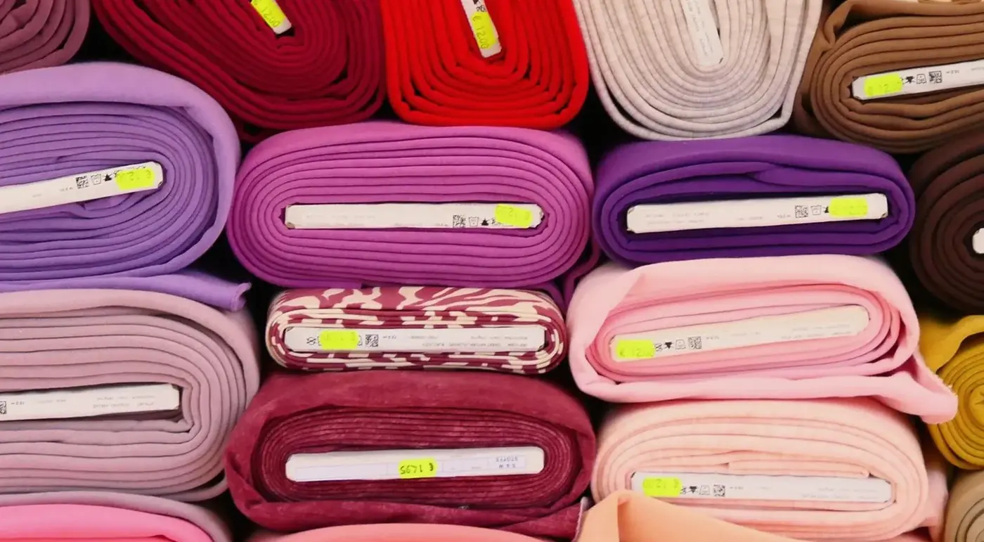 Rolls of dyed fabric stacked on a shelf